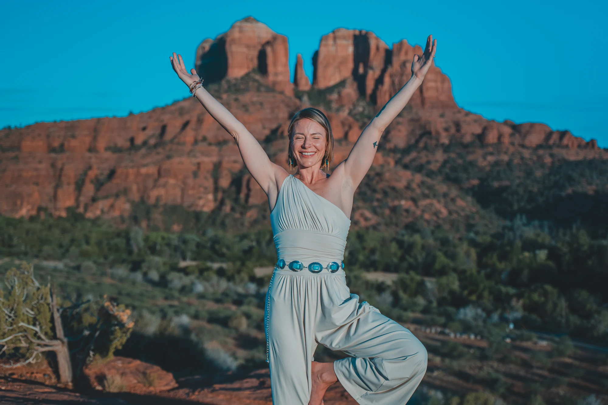 Chelsea standing with both arms raised, Cathedral Rock behind her
