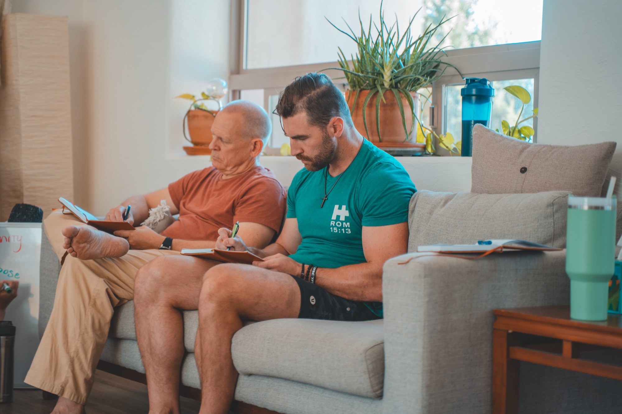 Two founders journaling side by side on a couch during a retreat session