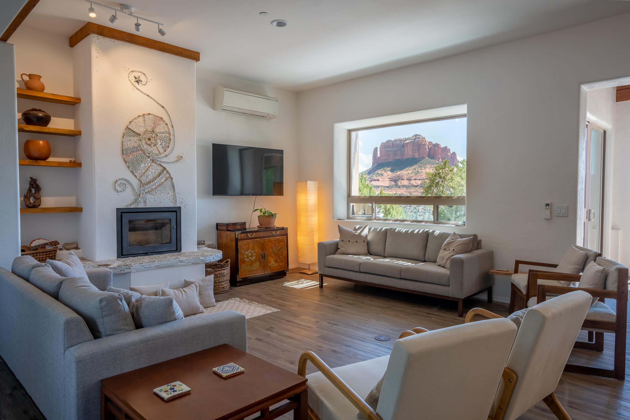 Living room with a wood-burning fireplace, comfortable seating, and warm natural light